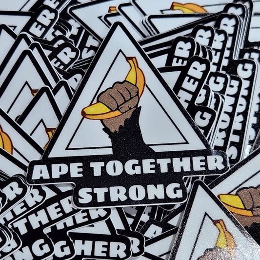 Stack of 'Ape Together Strong' stickers with graphic design on a wooden surface