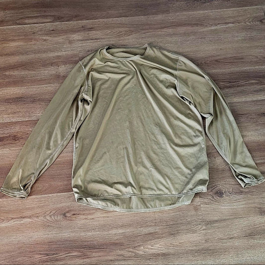 A long-sleeve crewneck shirt in a muted olive green color, laid flat on a brown wood plank floor.