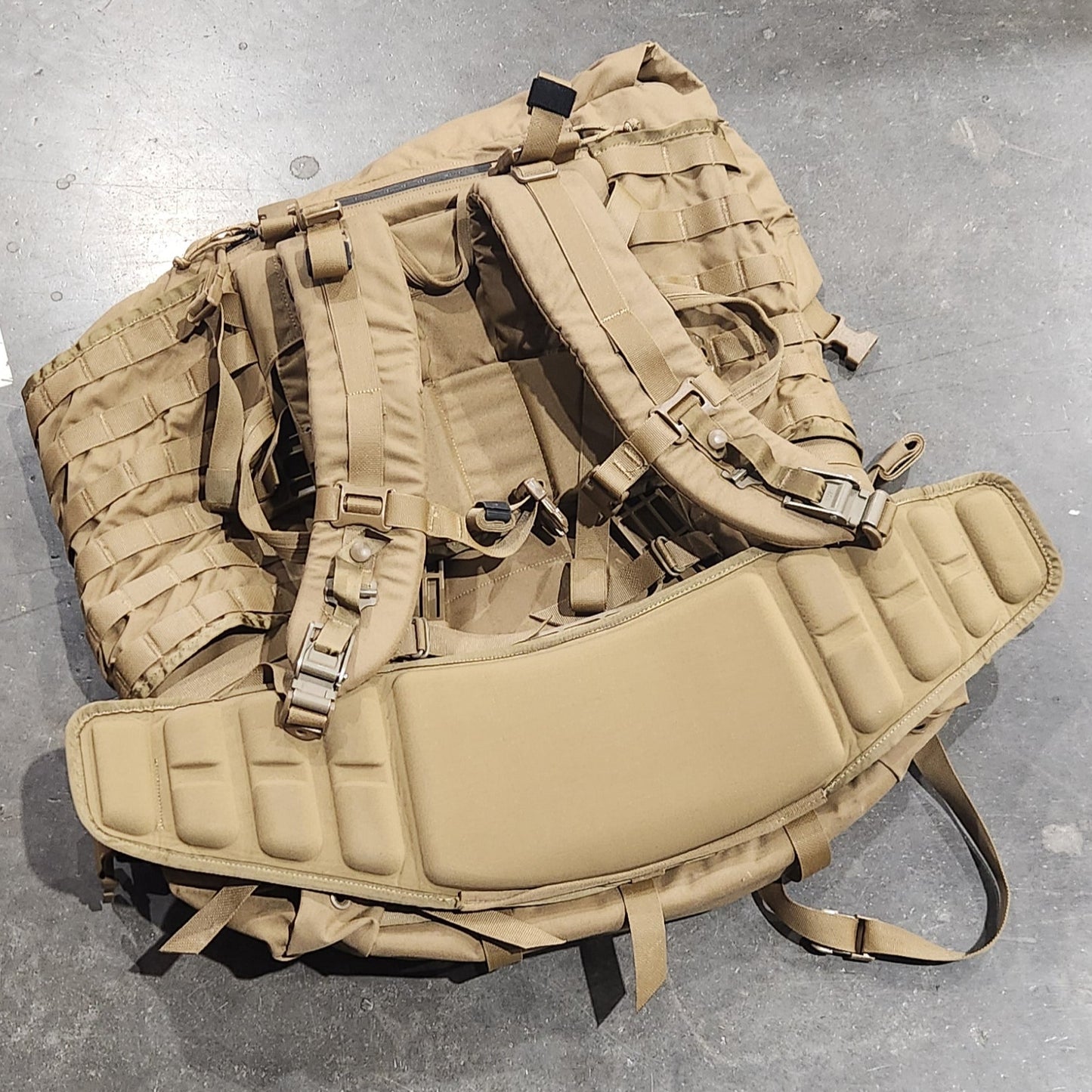 Tan tactical backpack on a gray floor