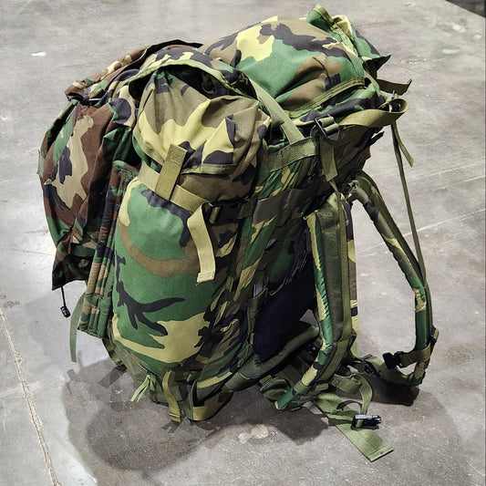 Camouflage backpack on a concrete floor with people in the background