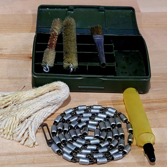 Gun cleaning kit with brushes, chain, and pump on a wooden surface