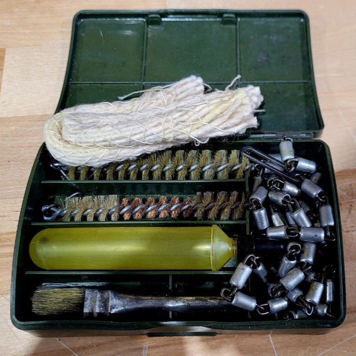 Assorted items including a green container, white rope, and metal components on a wooden surface.