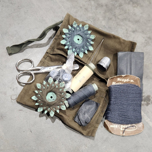 Crafting materials including yarn, scissors, and fabric on a concrete surface