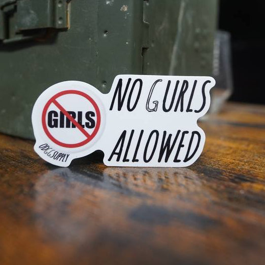 Sticker with 'No Girls Allowed' text on a wooden surface