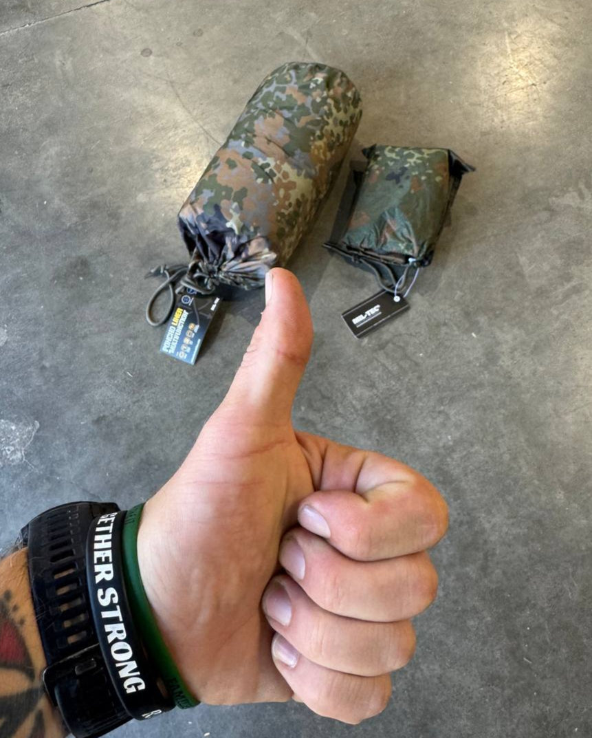 Hand giving a thumbs up with camouflage bags on a concrete floor