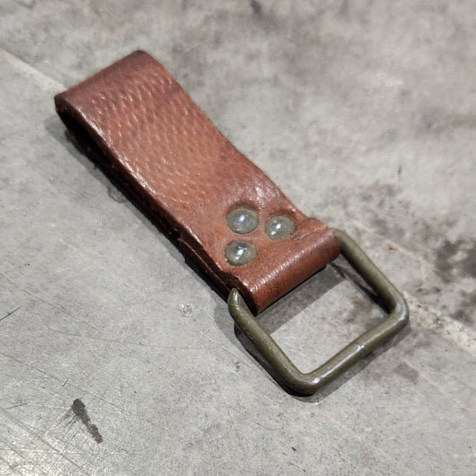 Brown leather bottle opener on a concrete surface