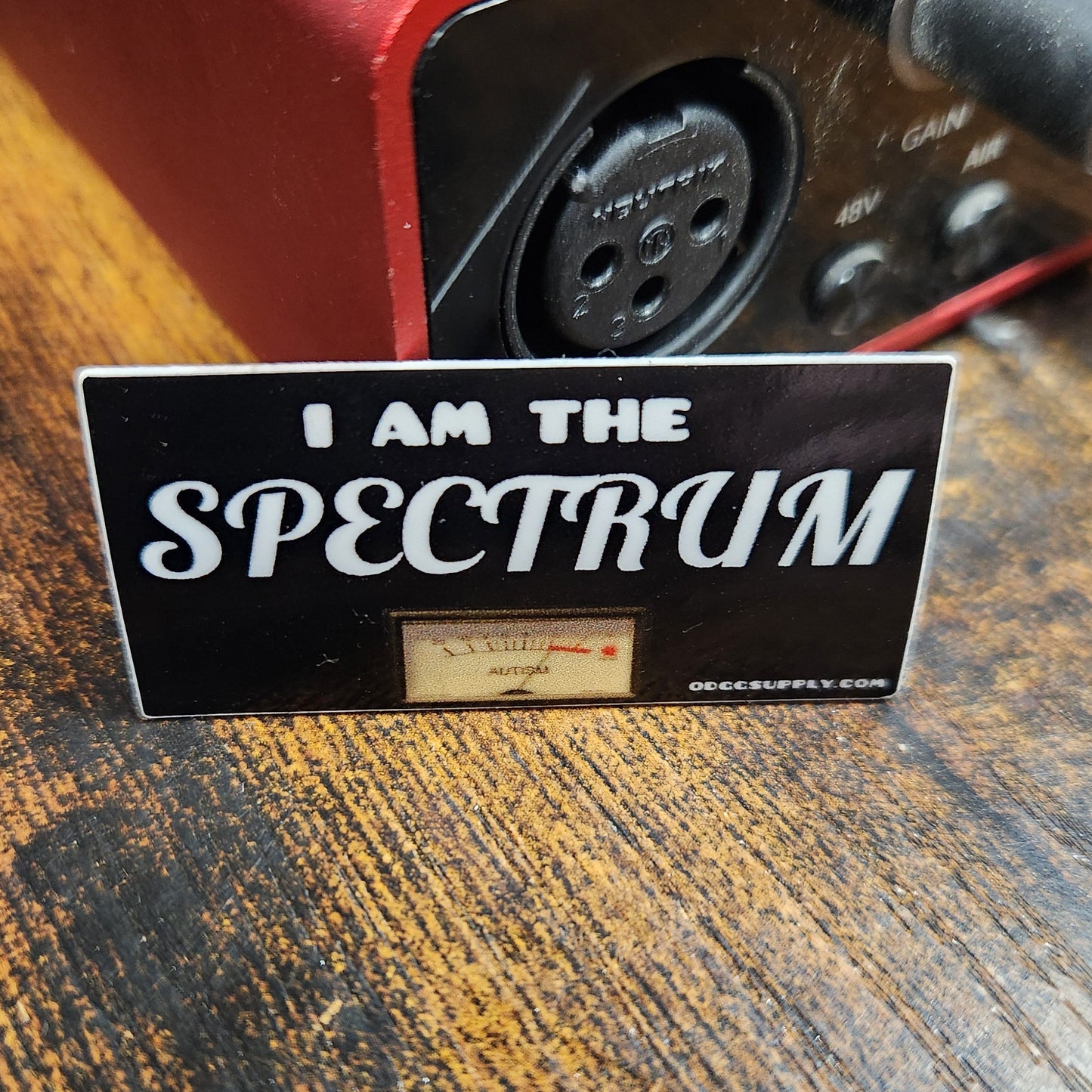 Sticker with 'I am the Spectre' text on a wooden surface