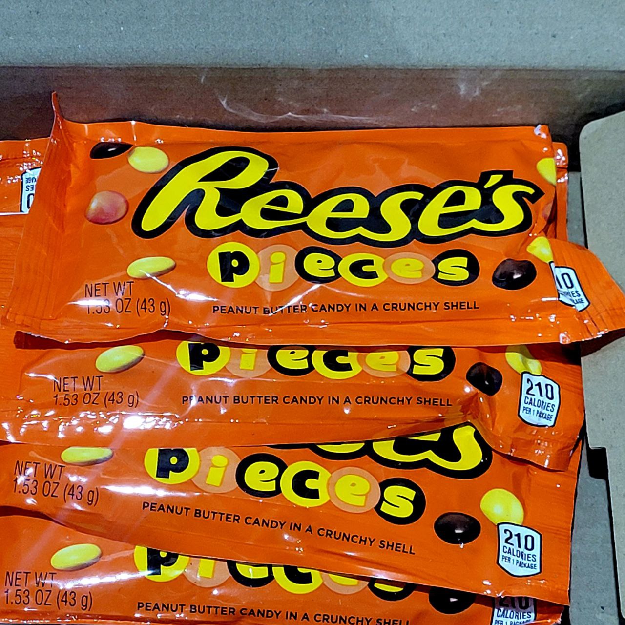 Multiple packages of Reese's Pieces candy stacked on a surface.