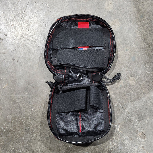 Black travel bag with red accents on a gray concrete surface