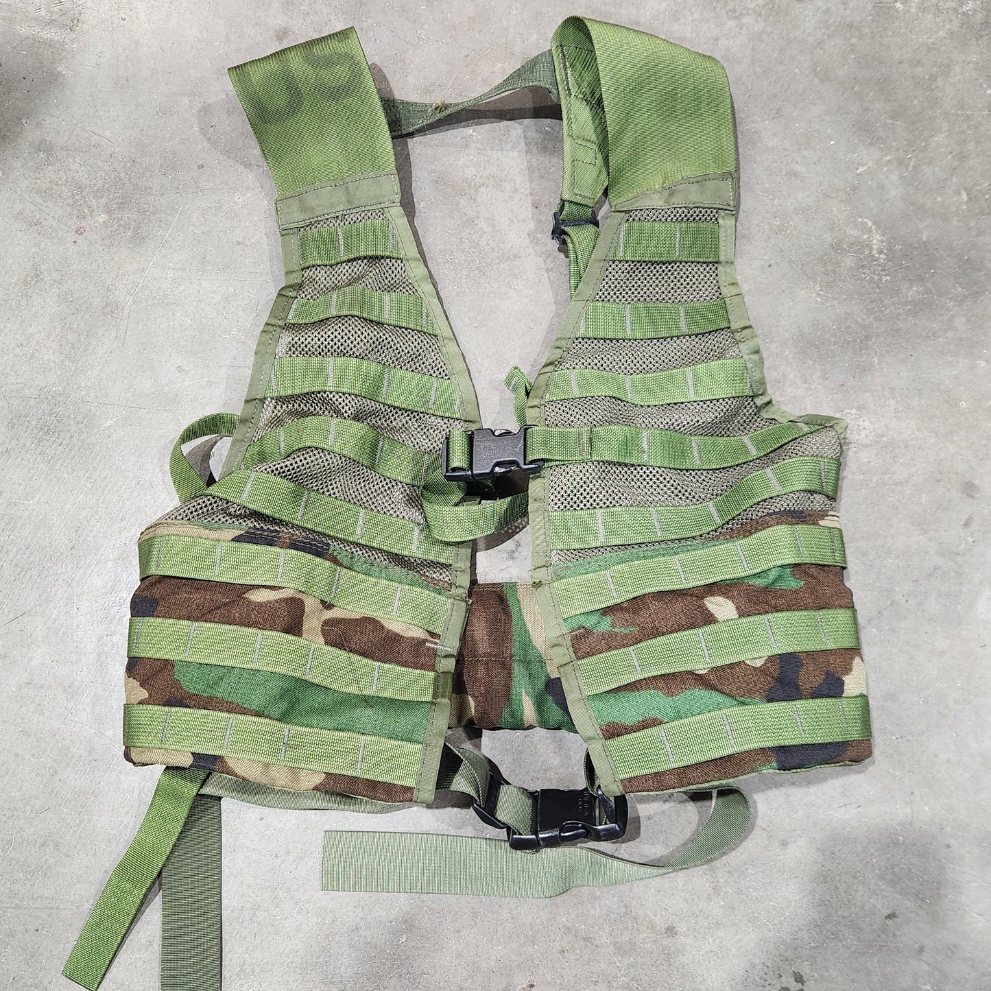 Green camouflage vest on a concrete floor
