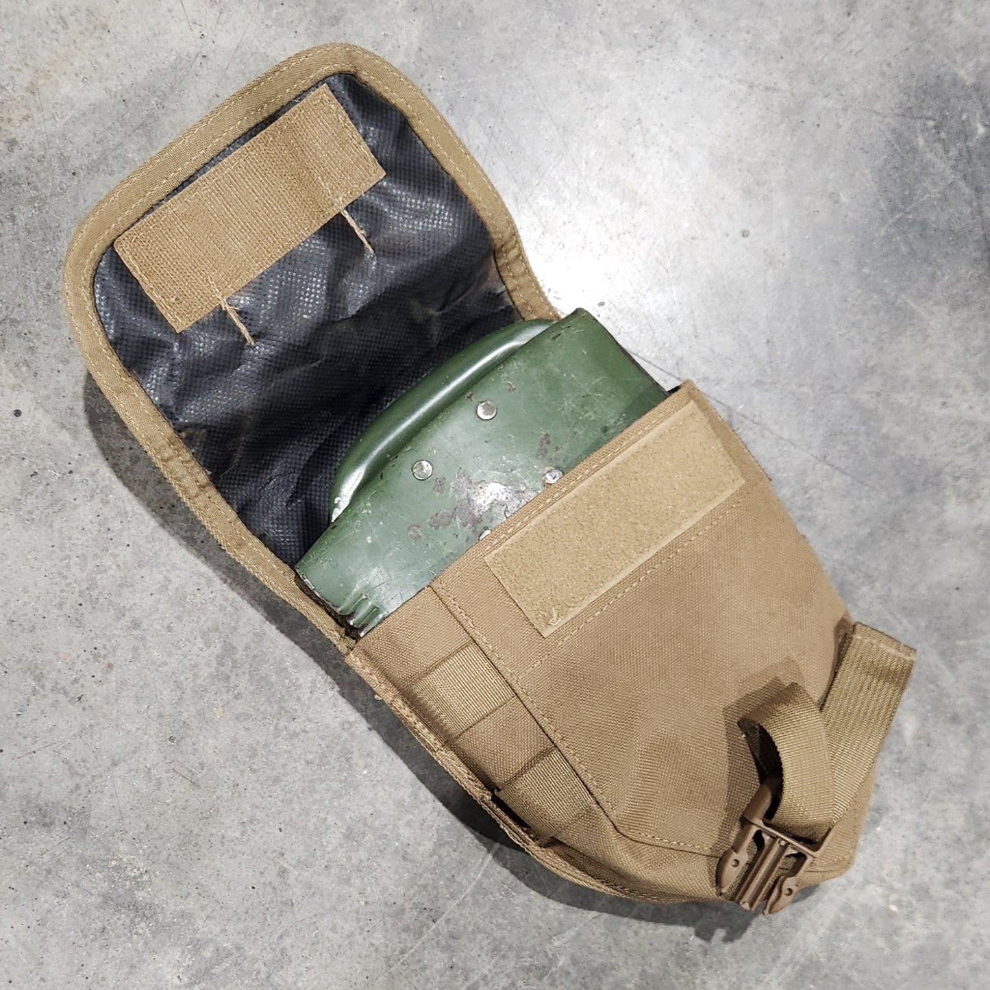 Brown tactical pouch on a concrete floor with a green object inside