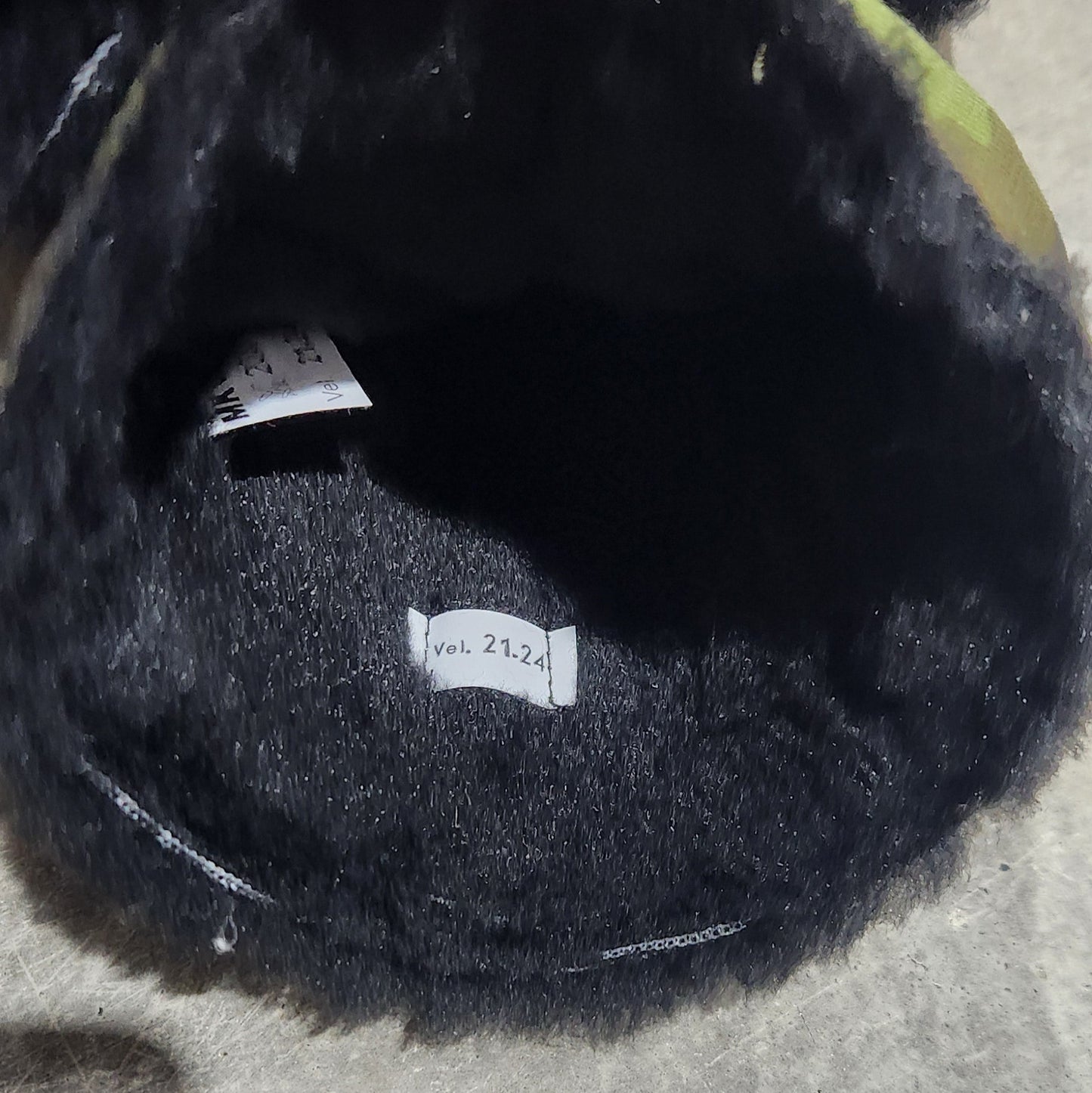 Black fur-lined item held by a hand on a concrete surface