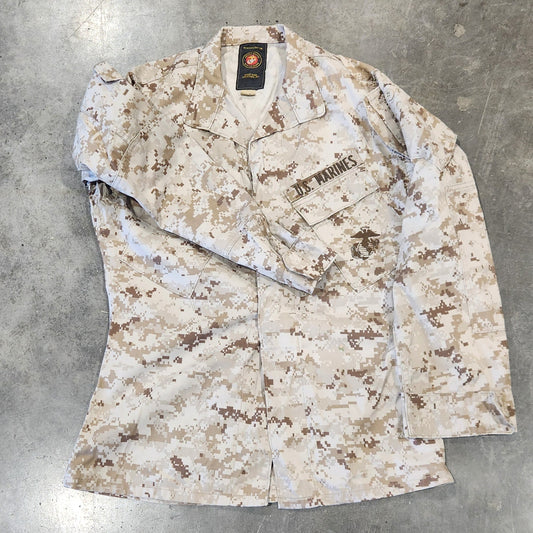 Camouflage-patterned jacket on a concrete floor with tools in the background