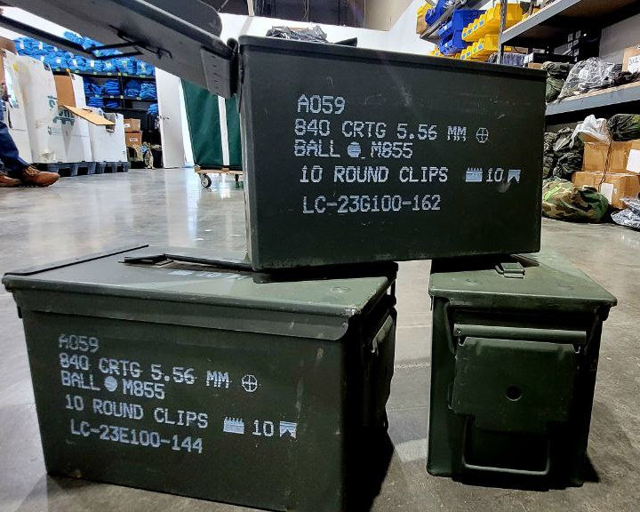 Green ammunition boxes with labels on a warehouse floor.