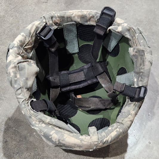 Camouflage helmet with straps on a concrete surface