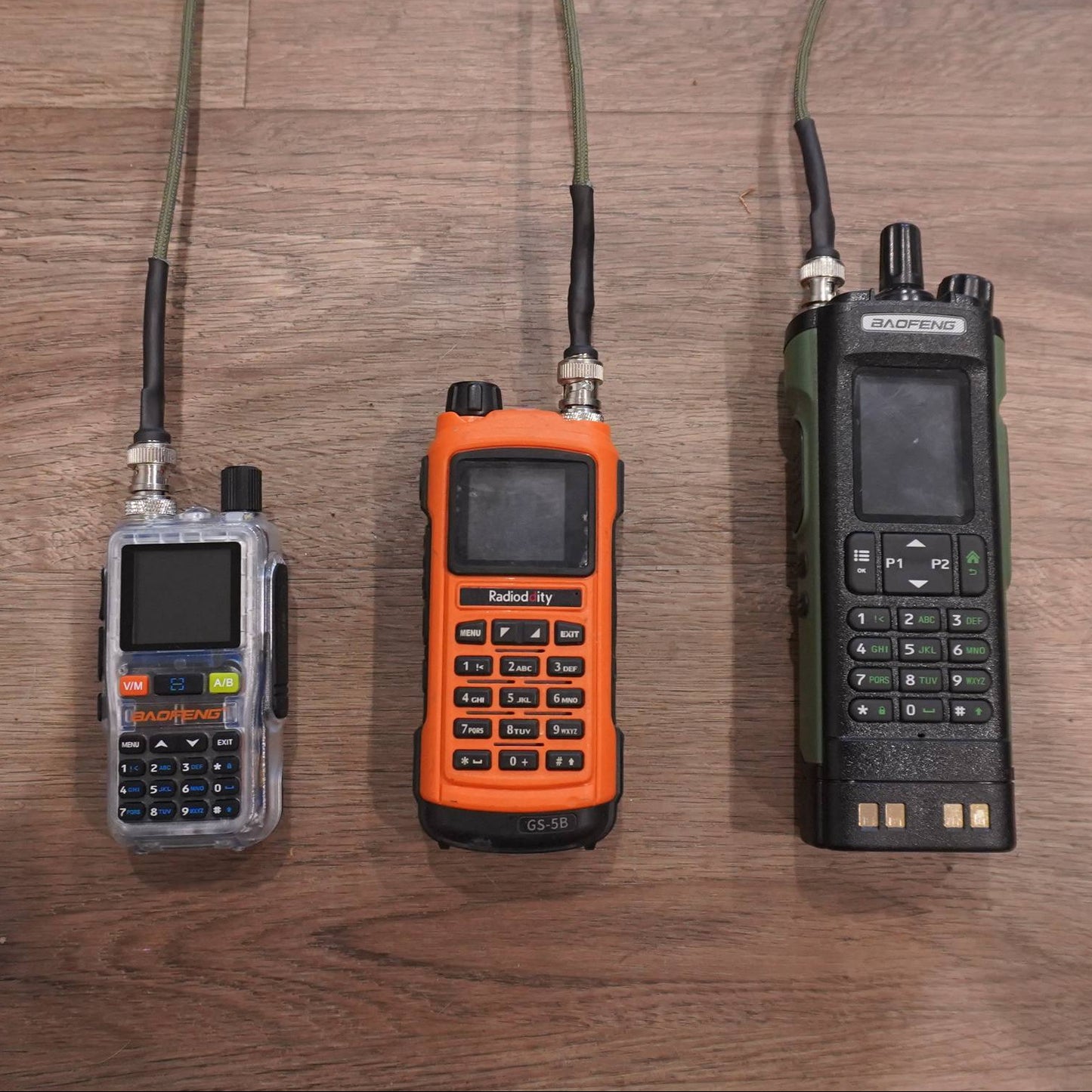 Three handheld radios on a wooden surface