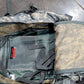 Camouflage backpack with visible branding on a gray floor