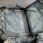 Camouflage backpack with open compartment on a concrete floor