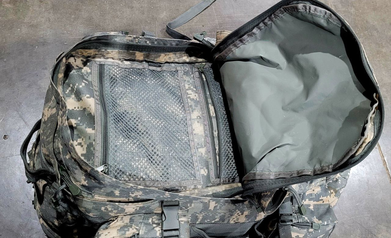 Camouflage backpack with open compartment on a concrete floor