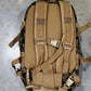 Tan tactical backpack with camouflage pattern on a concrete floor