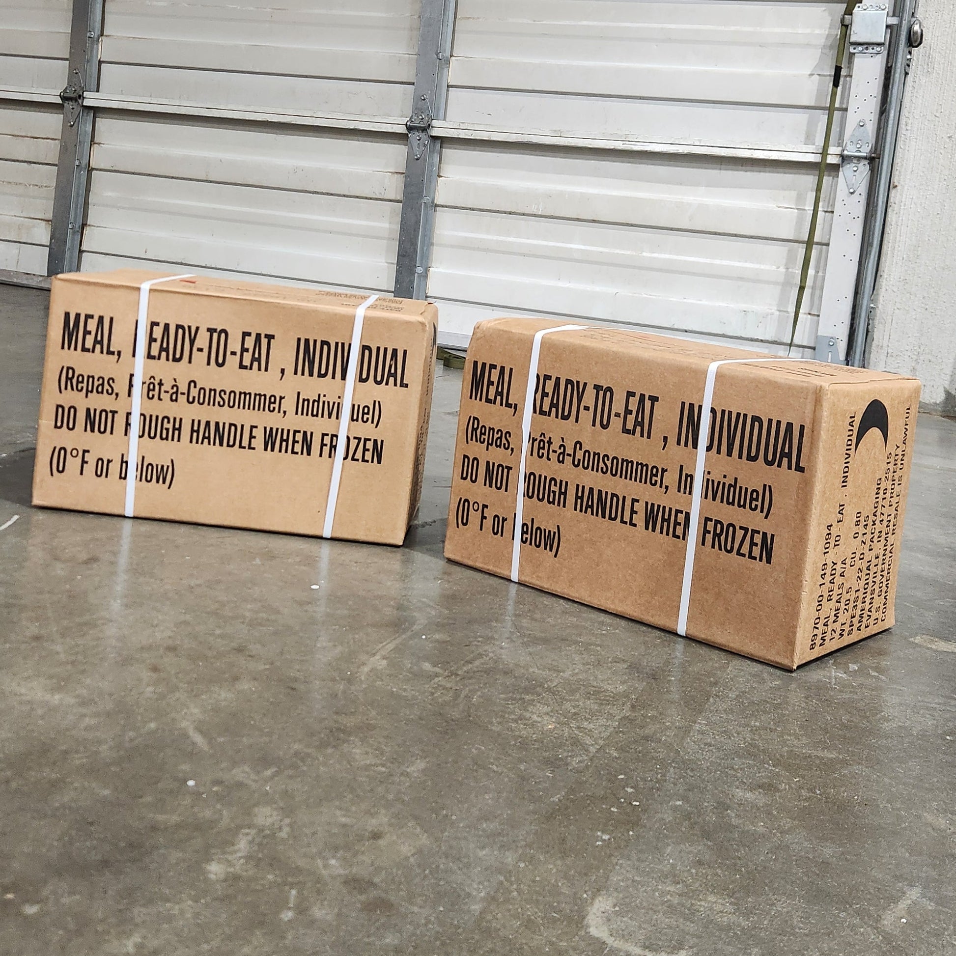 Two cardboard boxes on a metal pallet with a concrete floor in the background.