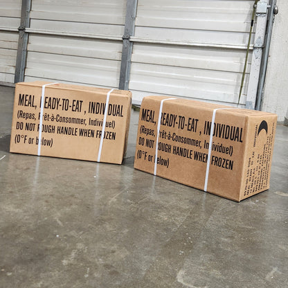 Two cardboard boxes on a metal pallet with a concrete floor in the background.