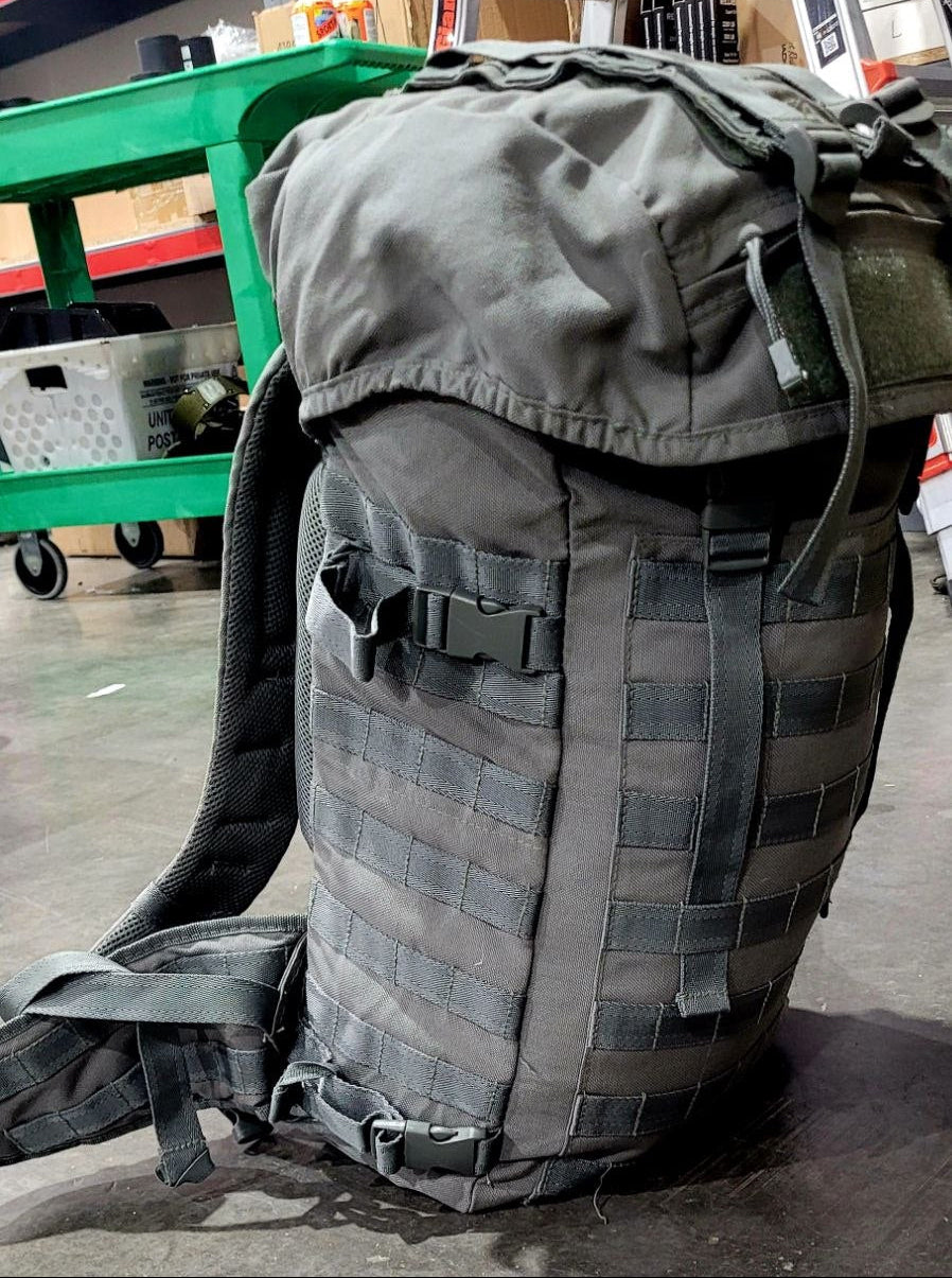 Gray tactical backpack in a warehouse setting