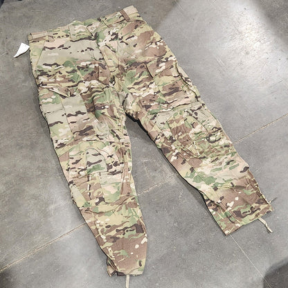 Camouflage pants on a concrete floor with a tool box and equipment in the background.
