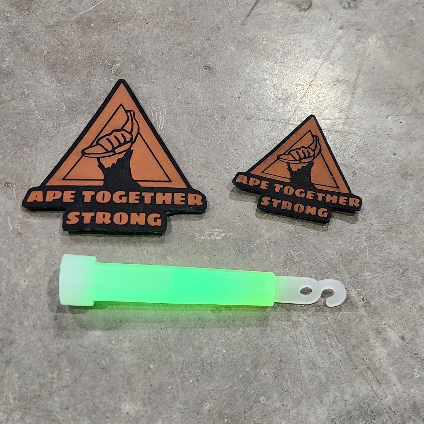 Two triangular patches with text and a green highlighter on a gray concrete surface