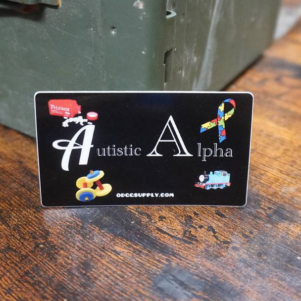 Sticker with 'Autistic Alpha' design on a wooden surface