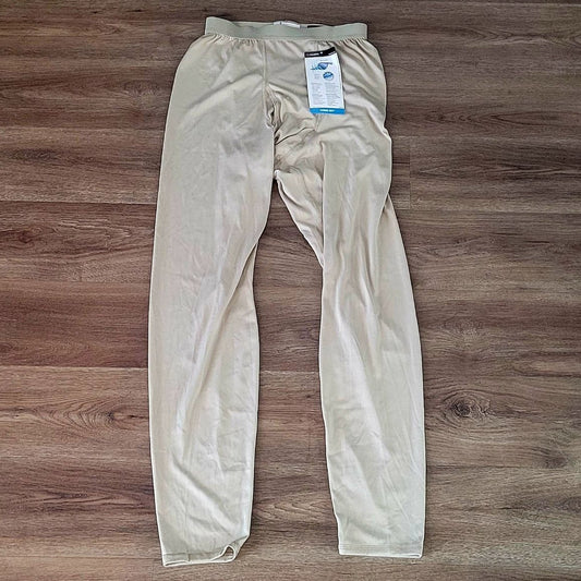 A pair of light beige compression pants laid flat on a brown wood-look floor, with a product tag still attached near the waistband.