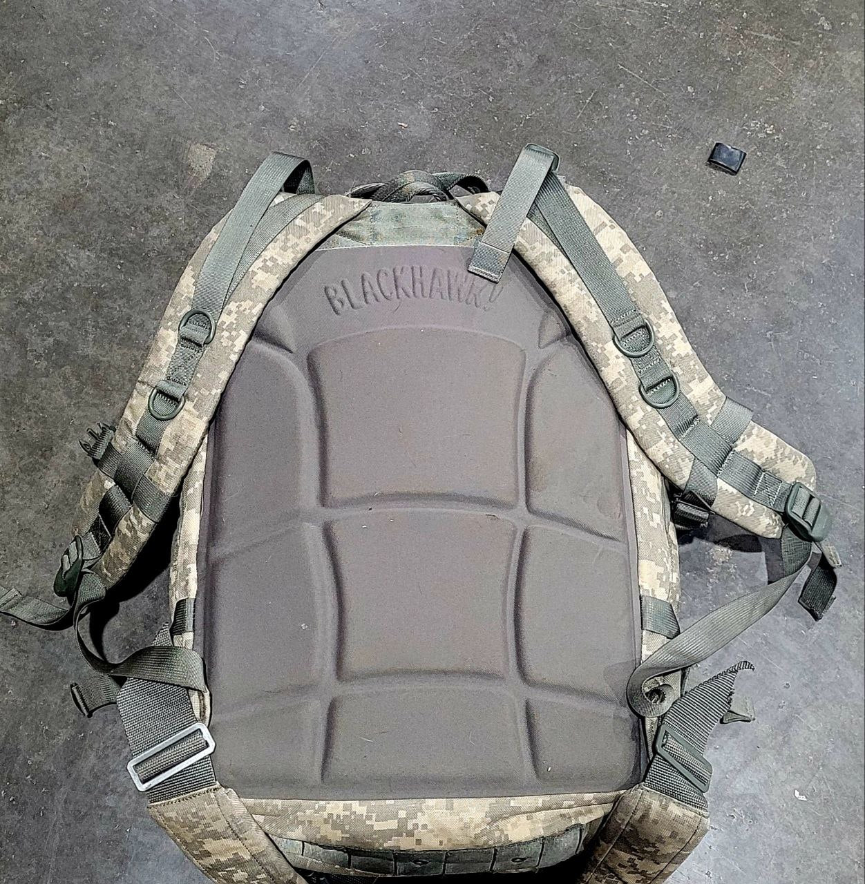 Tactical backpack with camouflage pattern on a gray surface