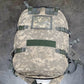 Camouflage backpack with multiple straps on a gray surface