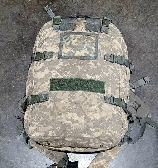 Camouflage backpack with multiple straps on a gray surface