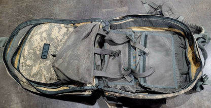 Open tactical backpack with camouflage pattern on a concrete floor