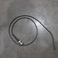 Coiled cable with a metal connector on a gray concrete floor