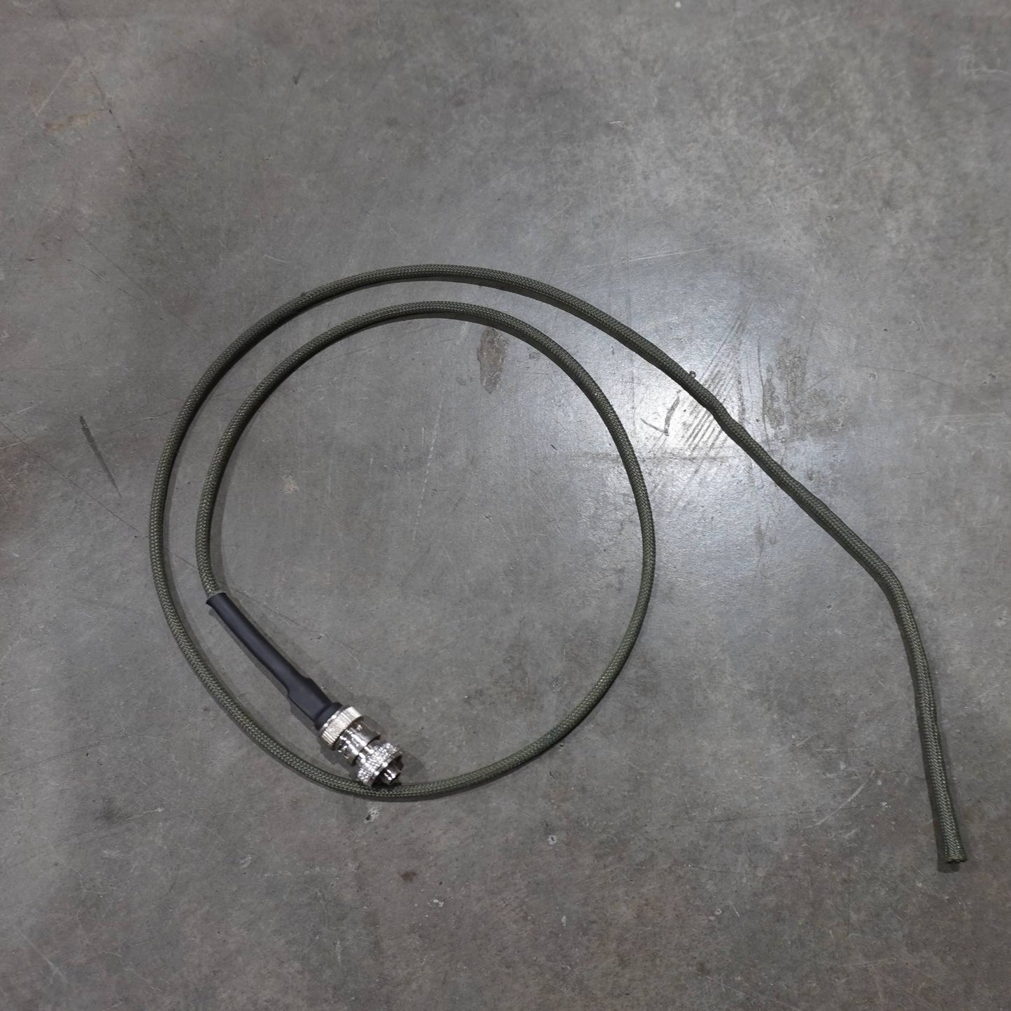 Coiled cable with a metal connector on a gray concrete floor