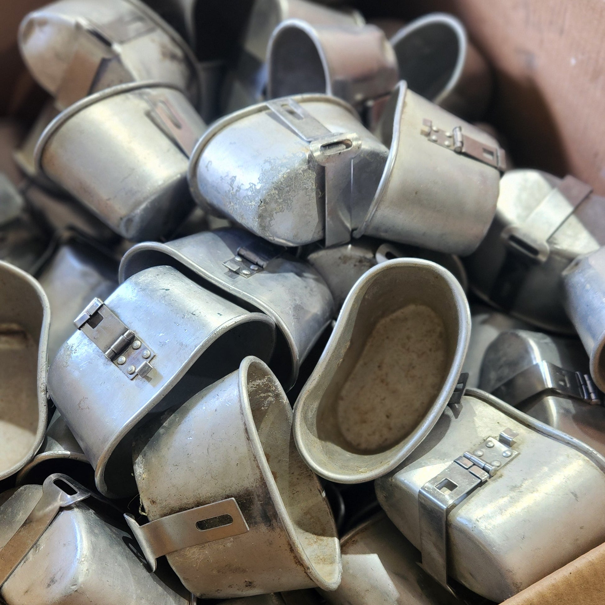 A cardboard box filled with multiple used silver metal horse boots, photographed from above.