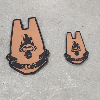 Two leather patches with a logo on a gray surface