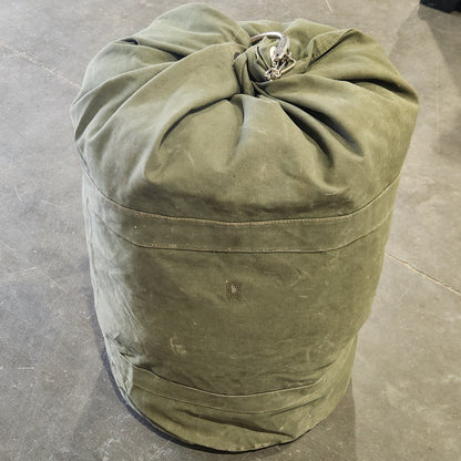 Green duffel bag rolled up on a concrete floor