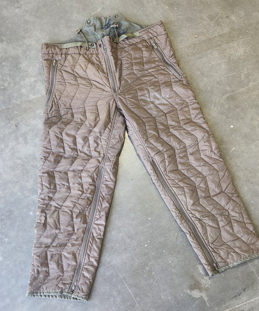 Brown quilted fabric on a concrete floor with a person's feet visible.