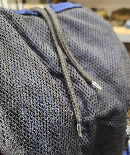 Close-up of a dark gray mesh pocket with a drawstring closure on a blue bag, showing the texture of the mesh material.