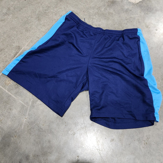 A pair of athletic shorts in dark blue with light blue side panels, laid flat on a gray concrete floor.