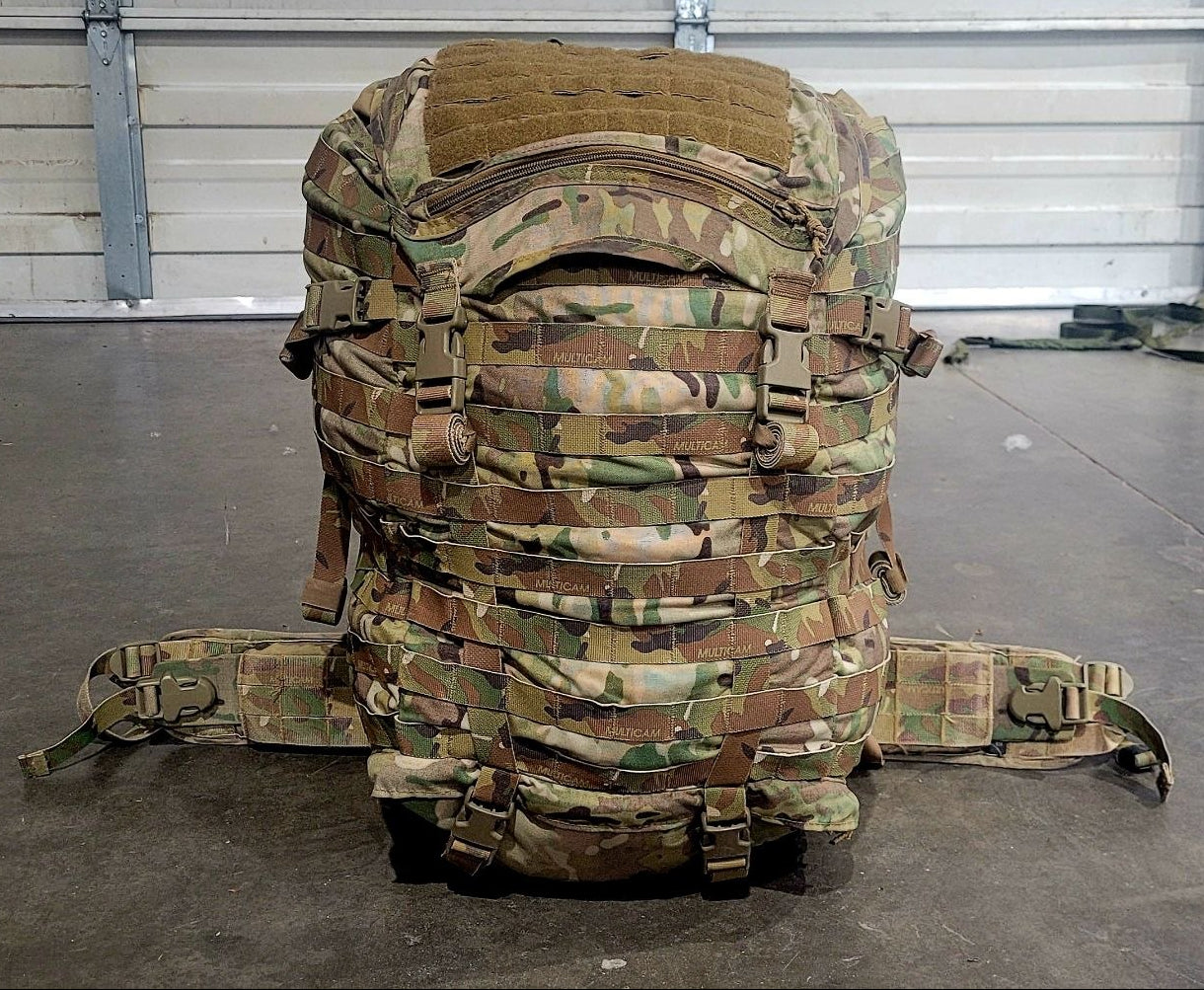 Camouflage backpack on a concrete floor with a metal door in the background