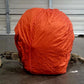 Orange vehicle cover on a rucksack in front of a metal garage door.