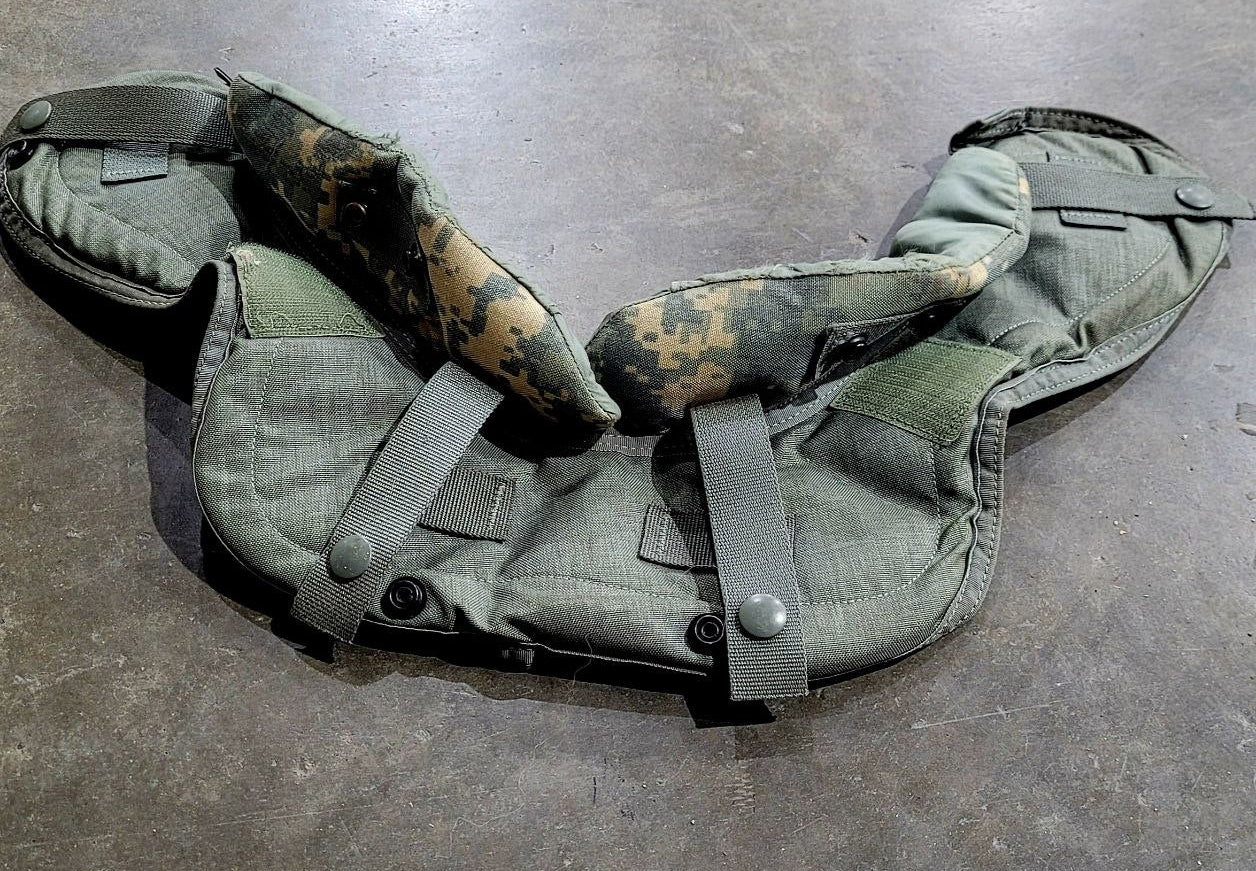 Green tactical vest with camouflage padding on a gray surface
