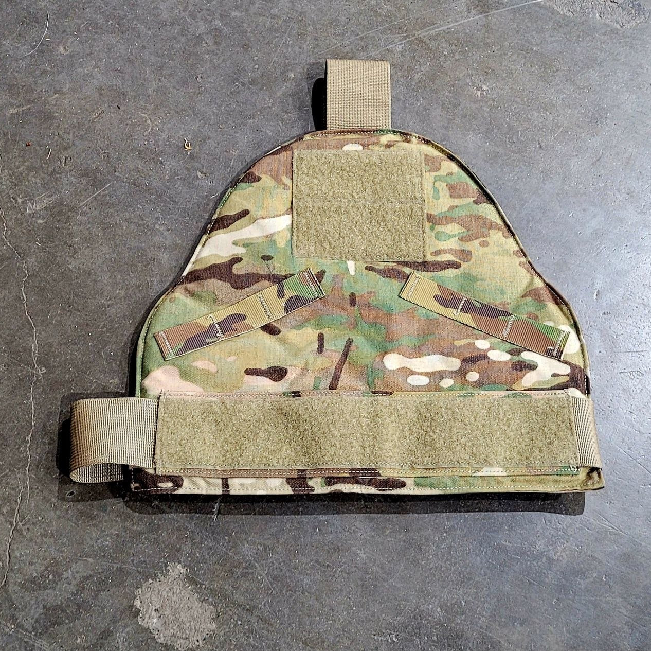 Multicam-patterned tactical plate carrier on a gray surface