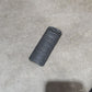 Several black textured cylindrical grip or handle components arranged on a gray concrete floor next to a cardboard box.