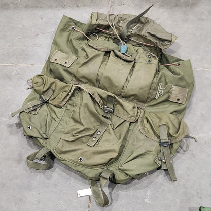 Green military-style backpack on a gray tiled floor