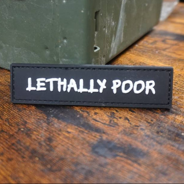 Text patch labeled 'LETHALLY POOR' on a wooden surface with a green metal box in the background.